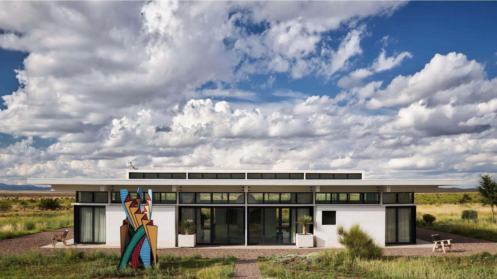 Modesthouse front elevation under a cloud-filled sky